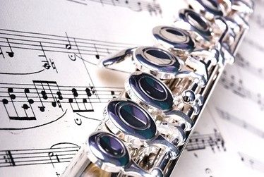 a silver flute on a sheet of music